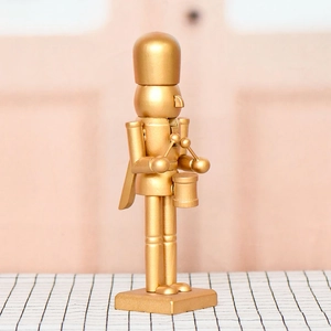 Golden nutcracker soldier drumming figurine with matte gold finish on checkered base