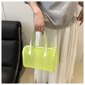 Detalle del bolso cilíndrico de malla verde neón con asas de cuero sintético y cremallera