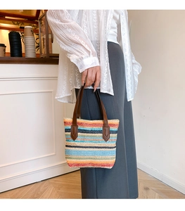 Close-up of vibrant rainbow striped woven tote bag with premium brown leather handles