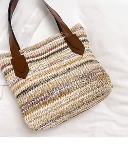 Detail view of woven straw tote bag featuring brown leather handles and striped texture