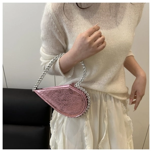 Detail of pink heart-shaped bag featuring metallic cracked leather and rhinestone edges
