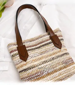 Detailed close-up of woven straw tote bag texture with brown faux leather handles
