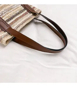 Detail of woven straw texture and premium brown leather handle with neat stitching