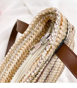 Detail of silver metal zipper and durable brown leather strap on woven straw beach bag