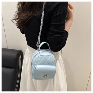 Detailansicht eines hellblauen Stepp-Minirucksacks mit silberner Kette an einem Model