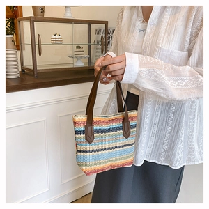 Detail of colorful striped woven straw tote bag with brown faux leather handles