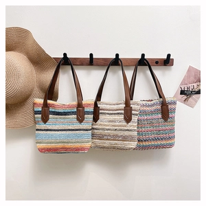 Detailed view of hand-woven striped straw tote bags with premium brown leather handles