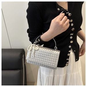 Detail of silver woven shoulder bag with pearl bow charm and metal chain handle