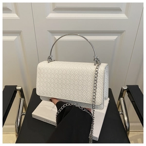 Close-up of white woven leather handbag with silver ring handle on minimalist background