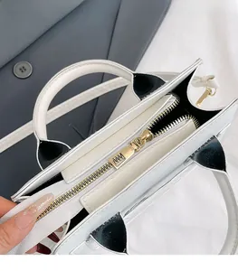 Detailed close-up of premium gold metal zipper and black trim on minimalist handbag