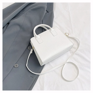 Minimalist white leather crossbody handbag with textured folds and metallic side zipper