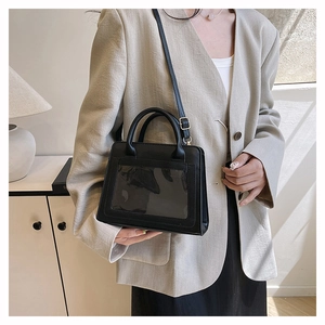 Detail einer schwarzen Lederhandtasche mit klarem PVC-Fenster und Schultergurt