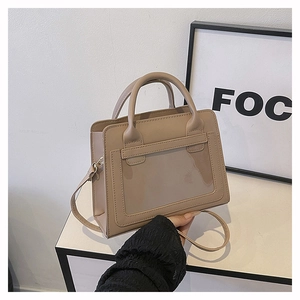Detail of beige faux leather handbag with stitching, top handles and shoulder strap