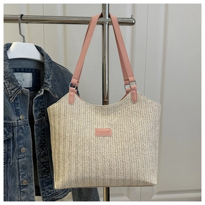 Detail of herringbone weave texture and pink faux leather fashion label on a woven tote