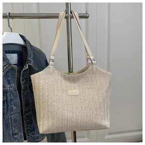Detail of cream woven tote bag with FASHION leather patch and dual shoulder straps