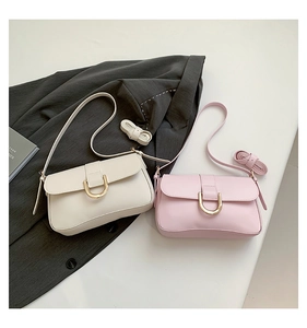 Detail of minimalist cream and pink crossbody bags with elegant gold U-shaped metal buckles