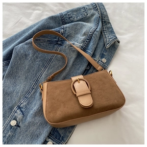 Vue détaillée du sac marron rétro avec texture daim et boucle dorée sur du denim