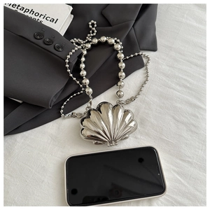 Detailed view of silver shell-shaped mini bag with large bead chain and phone size reference