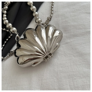 Detail of silver shell-shaped mini bag featuring metallic chrome finish and bead chain
