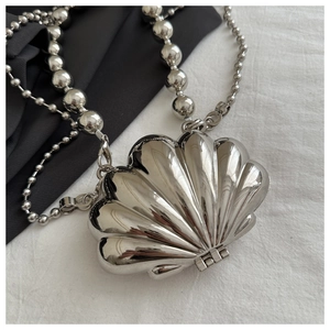 Close-up of a silver shell-shaped mini bag featuring a metallic beaded shoulder strap