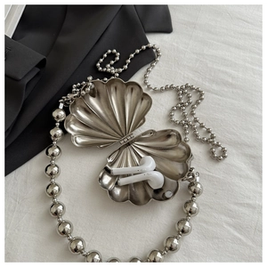 Detail of silver shell-shaped mini bag with large round bead handle and metal finish