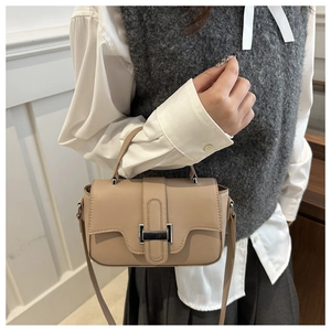 Detail view of khaki square handbag with silver metal buckle on a model outfit