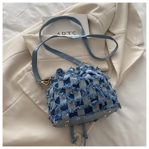 Dettaglio della borsa a secchiello in denim a scacchi con frange e tracolla in pelle