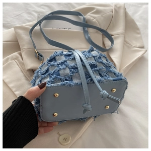 Dettaglio della borsa a secchiello in denim a scacchi con piedini in metallo e frange