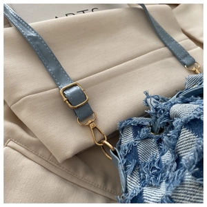 Dettaglio della borsa in denim a scacchi con bordi sfrangiati e tracolla in pelle blu