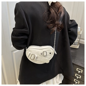 Détail du sac à bandoulière en forme de cœur avec boucles argentées et chaîne