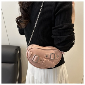 Sac à bandoulière rose en forme de cœur avec boucles argentées porté par le modèle