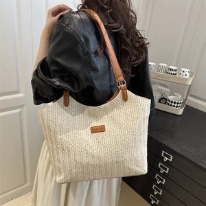 Minimalist woven straw tote bag with brown leather straps and fashion label detail