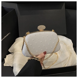 Detail of white jacquard clutch bag with gold rhinestone clasp and chain strap