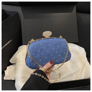 Detail of blue denim evening bag with rhinestone clasp and gold chain strap