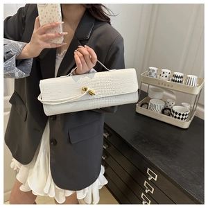 Détail du sac baguette blanc à texture croco avec un fermoir à nœud doré chic