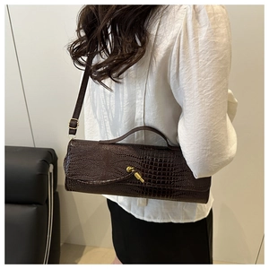 Détail du sac baguette marron foncé à motif crocodile avec fermoir doré et bandoulière