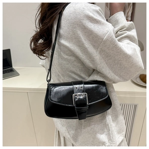 Detail of minimalist black patent saddle bag featuring a large silver metal buckle strap