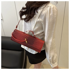 Detail view of deep red crocodile texture handbag with a vintage gold clasp on model