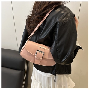 Side view of a light pink leather baguette bag with silver buckle on a female model