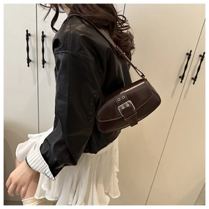 Detail of dark brown leather handbag featuring a large stylish decorative buckle