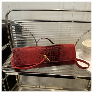 Détail d'un sac à main rouge effet crocodile avec fermoir doré sur étagère métallique