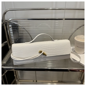 Détail du sac baguette blanc à motif crocodile avec fermoir nœud doré et poignée supérieure