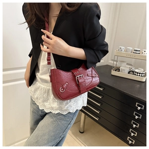 Detailed close-up of dark red crocodile pattern leather with silver rivets on saddle bag