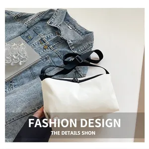 Detailansicht der weißen Nylon-Umhängetasche mit verstellbarem Gurt auf Jeansjacke