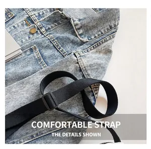 Detail eines verstellbaren schwarzen Schultergurts und blauer Denimstoff mit Metallteilen