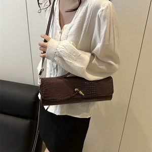Sac baguette marron foncé en cuir de crocodile avec une boucle métallique à nœud dorée