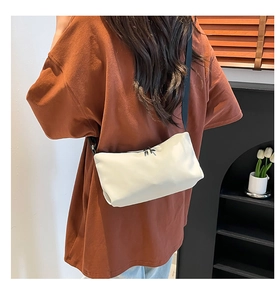 Details einer minimalistischen weißen Kuriertasche aus Leder mit weicher Textur und Gurt