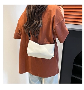 Detailansicht der weißen minimalistischen Umhängetasche aus Leder mit schmalem Gurt am Model