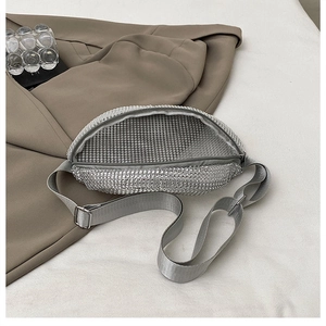 Detail of silver rhinestone waist bag featuring adjustable nylon strap and metal zipper