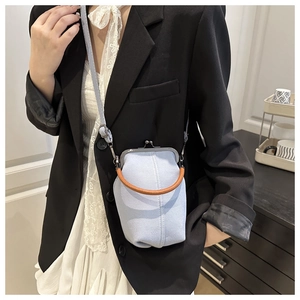 Detail of light blue denim crossbody bag with vintage metal clasp and woven handle